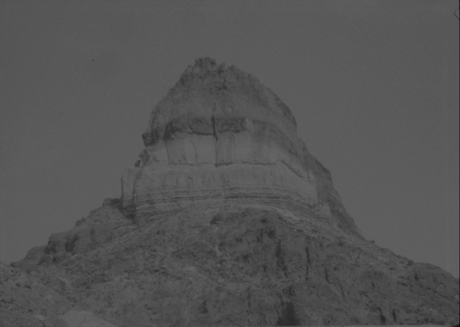 Black-and-white 16mm still from I Woke Up in the Morning: a craggy mountain peak in Terlingua, Texas against a hazy sky